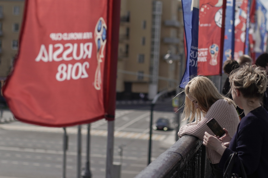 Women look over from the Krymsky Bridge, adorned with banners of the 2018 soccer World Cup, in Moscow, Russia, Wednesday, June 13, 2018. A senior Russian lawmaker advised Russian women Wednesday to be vigilant during any romantic encounters with foreign fans flocking to Russia for the World Cup so as not to end up raising their children alone. (AP Photo/Victor R.