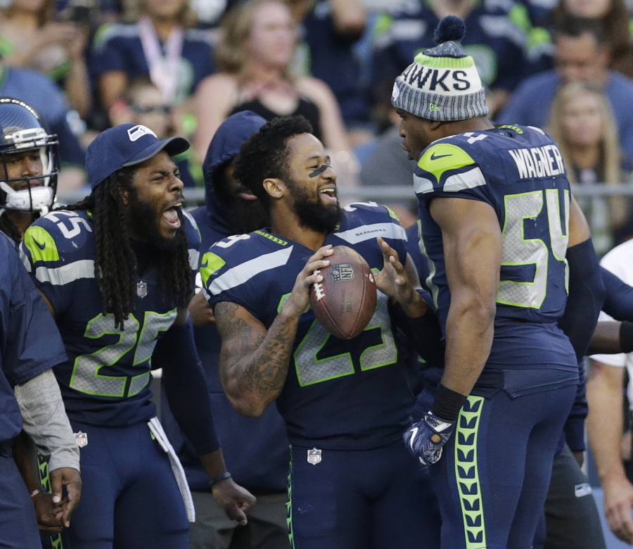 FILE - In this Aug. 25, 2017, file photo, Seattle Seahawks cornerback Richard Sherman, free safety Earl Thomas, center, and middle linebacker Bobby Wagner (54) react on the sideline during the second half of an NFL football preseason game against the Kansas City Chiefs, in Seattle. Thomas is putting the pressure on the Seattle Seahawks for a new contract, saying he will not participate in any team activities until his contract situation is resolved. That includes the upcoming mandatory minicamp.