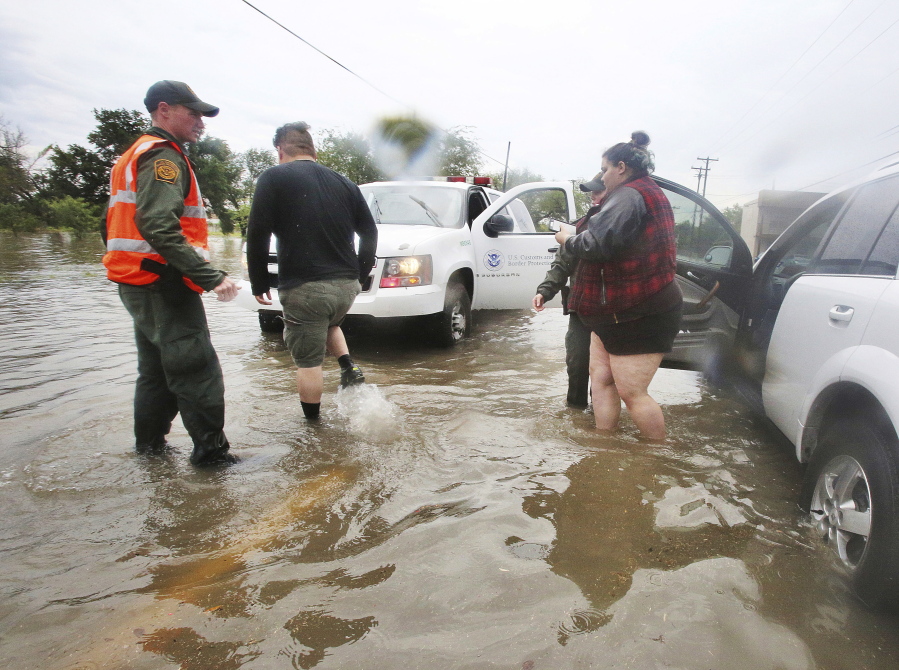 U.S. Border Patrol agents help a stranded motorist on Bryan Road after heavy rains caused water to rise and flood whole neighborhoods, Thursday, in Mission, Texas.