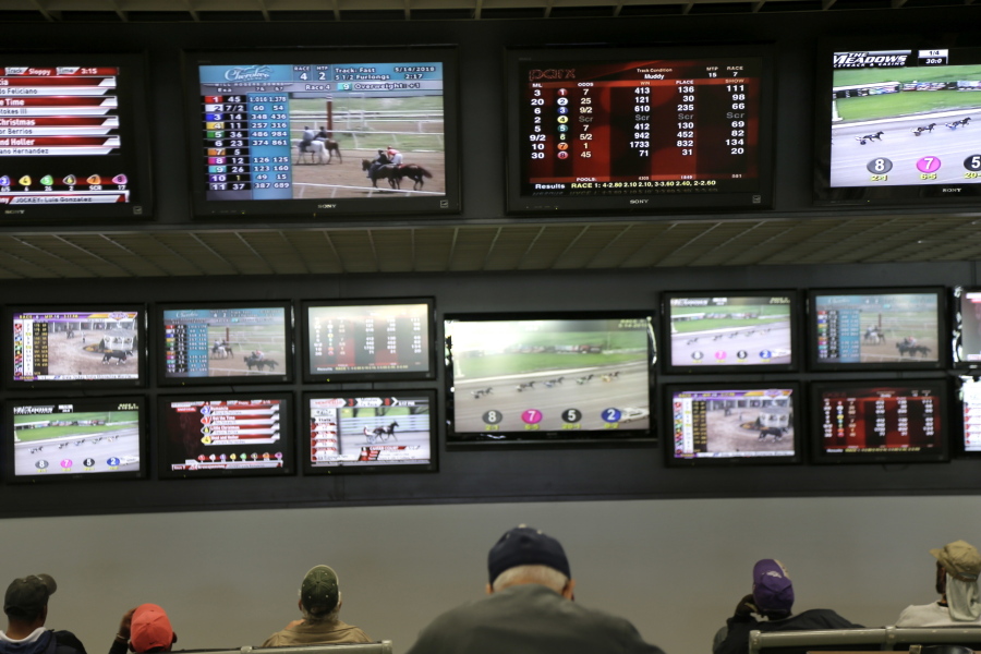 FILE - In this May 14, 2018, file photo, men watch horse racing on an array of screens at Monmouth Park Racetrack in Oceanport, N.J. New Jersey lawmakers are facing some key decisions Monday, June 4, as they race to legalize sports betting after winning a case in the U.S. Supreme Court.