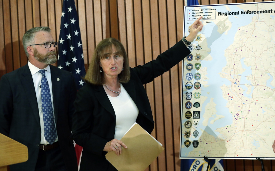 U.S. Attorney Annette Hayes, center, stands with FBI Special Agent in Charge Jay Tabb Jr., left, as she points to a map Wednesday during a news conference in Kent while discussing the arrest earlier in the day of approximately three dozen people connected with a violent drug-trafficking group in Western Washington. (Ted S.