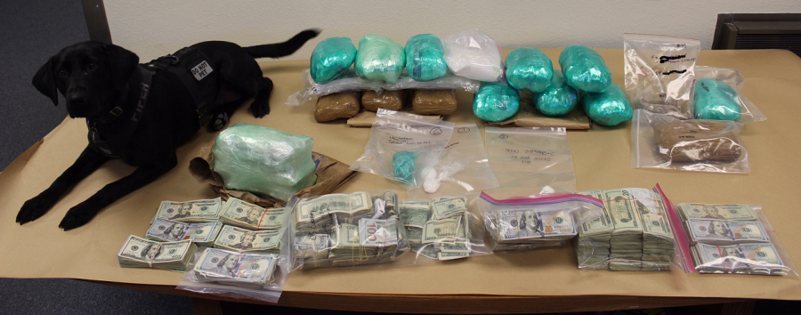Clark County Sheriff’s Office drug canine, Piper, sits with a cache of drugs and cash seized in late June as part of an investigation into a drug trafficking organization.