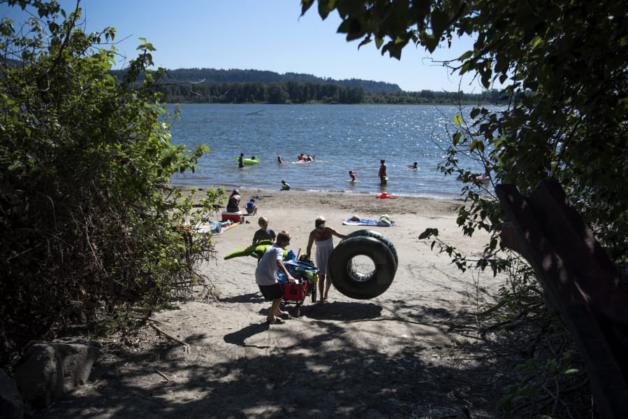 Andrew Helt, 12, left, his brother Patrick, 10, and their mother, Amy Brown, right, all of Washougal, make their way up the path after spending the afternoon at Cottonwood Beach in Washougal on July 11. Brown said the family visited Crown Park pool often in past summers so they’ve been trying to find new places to swim.