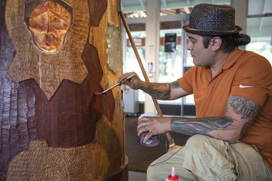 Yakama artist Toma Villa does some touch-up work Friday after repairing a crack in the wood in his Spirit Pole sculpture at the Fort Vancouver Visitor Center.