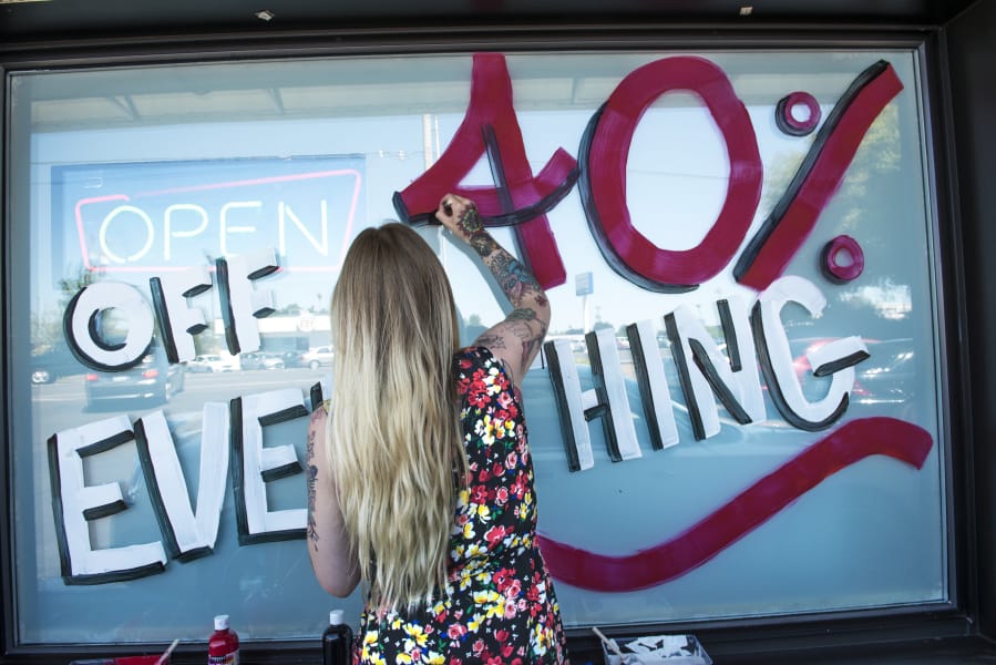 Jessie Leonetti, a budtender at Sticky’s Pot Shop, paints a sale announcement on the store’s window. The Hazel Dell pot shop will close soon after the state Supreme Court declined to hear their appeal to lift the ban on recreational marijuana sales in unincorporated Clark County.