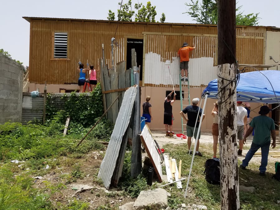 A team of volunteers paints the exterior of a home damaged in Hurricane Maria in Ponce, Puerto Rico. The 26-person group made up a trip organized by Forward Edge International, a Vancouver-based Christian nonprofit.
