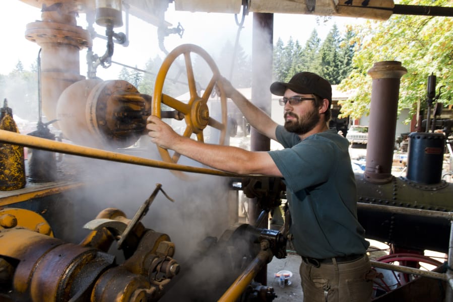 Ryan Johnson, of Amboy, operates a turn of the century Corliss steam engine Sunday at the Iron Ranch Antique Tractor, Engine Show and Flea Market in Ridgefield. The 600-horsepower steam engine once powered an entire sawmill in northern Washington.