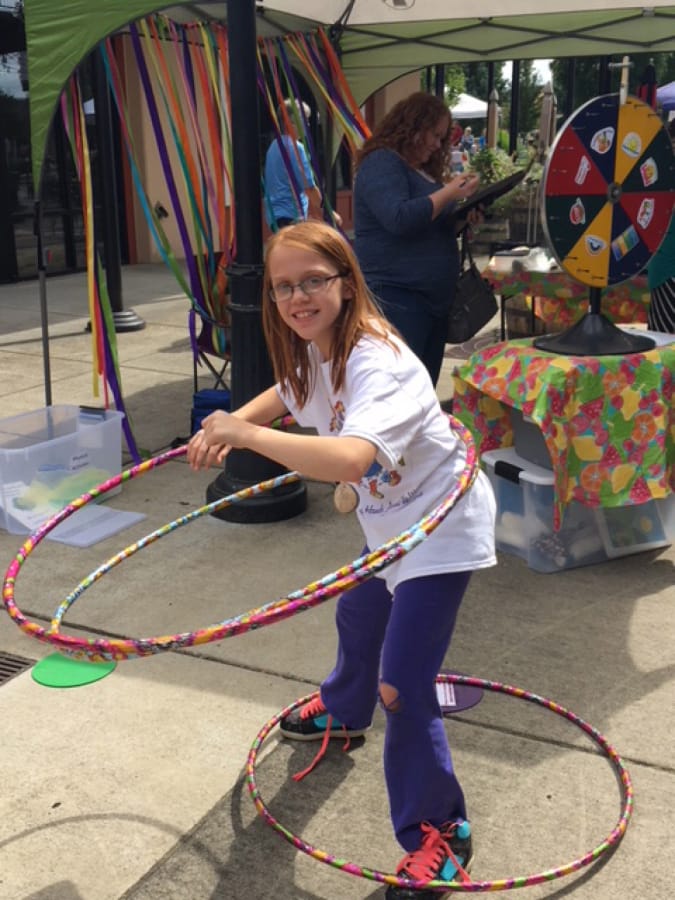 Battle Ground: Brynlee Hammond testing her hula hoop skills at Summertime YUM! booth at the Battle Ground Farmers Market. Washington State University Extension is traveling around to farmers markets this summer to go over health tips.