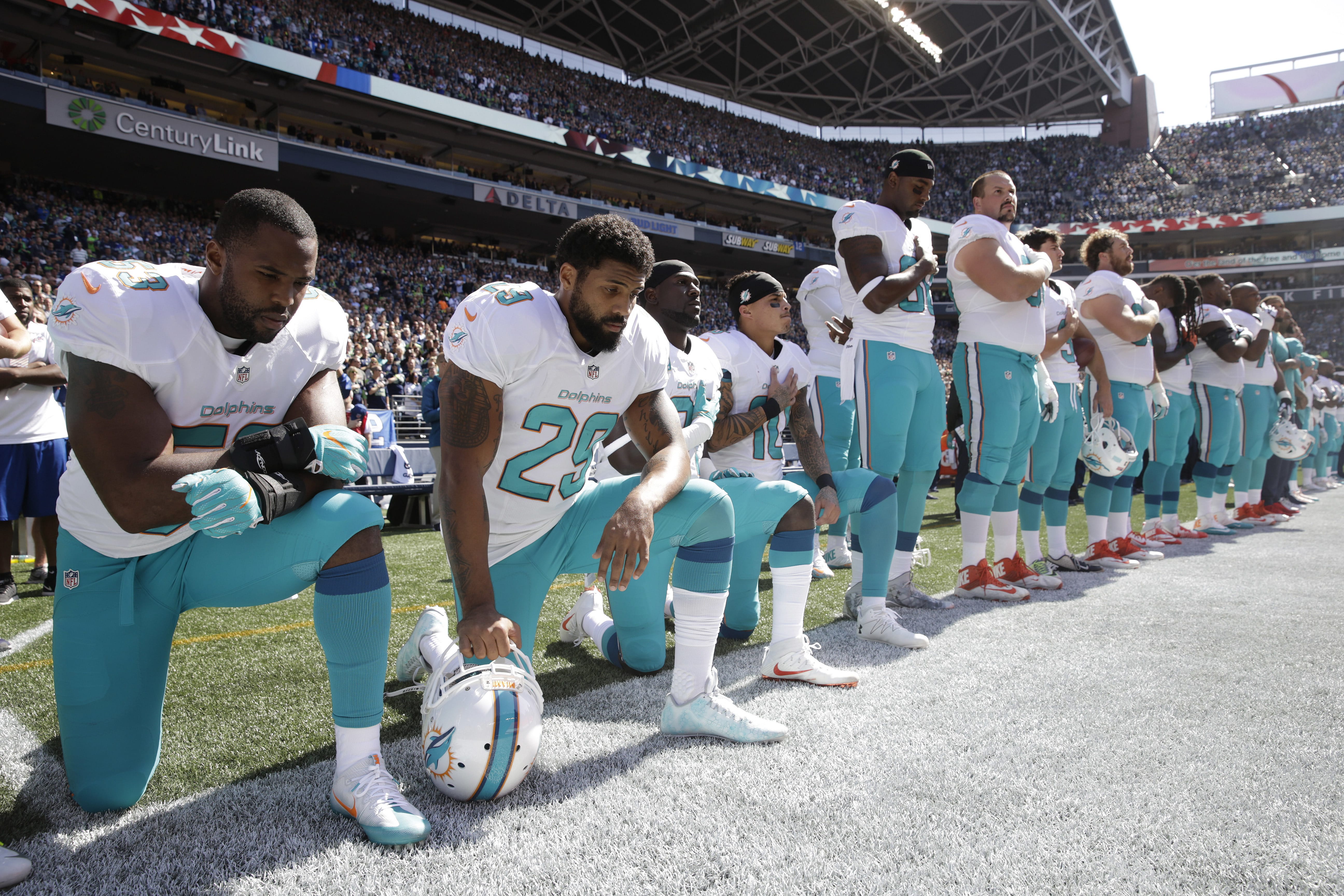 Miami Dolphins' Jelani Jenkins, Arian Foster, Michael Thomas, and Kenny Stills, kneel during the singing of the national anthem before a game against the Seattle Seahawks last season.