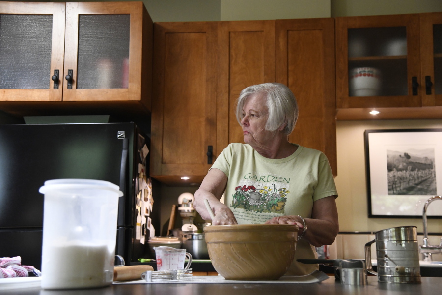Anne Hunt looks to her husband, Bruce, to be reminded if she added sugar to her dough in their home in Chicago on July 13. Diagnosed with Alzheimer’s in 2016, Anne, who once ran a Chicago cooking school, now has to separate the ingredients and mixing to two different sections of the kitchen to prevent errors.