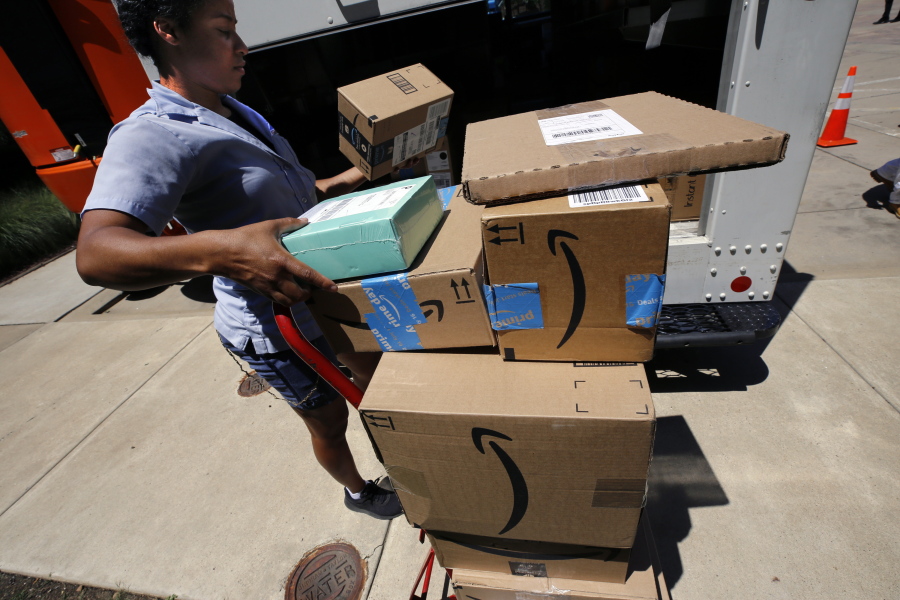 A U.S. postal carrier delivers Amazon orders to an apartment complex in downtown Pittsburgh on July 19. Amazon’s quarterly profit soared past $2 billion for the first time, as revenue from online shopping and its cloud computing business grew. Gene J.