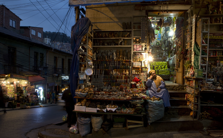 A woman sits at her shop of Andean amulets and offerings to the “Pachamama,” or Mother Earth, at the Witches’ Market in La Paz, Bolivia, on July 10. Left: Andean vessels and amulets are displayed for sale at a shop.