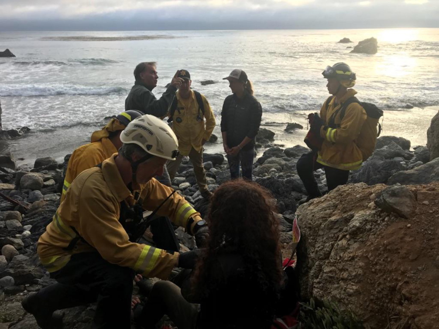 Authorities tend to Angela Hernandez, foreground center, after she was rescued, in Morro Bay, Calif. Authorities say a couple on a camping trip came upon Hernandez, from Oregon, who had been missing since July 6, after her car went over a cliff in coastal California.