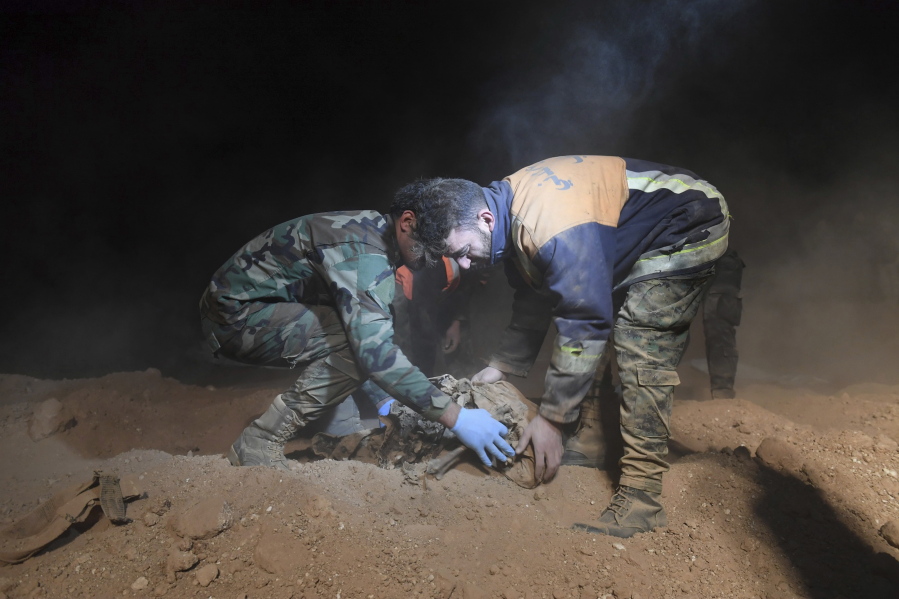 Syrian security force members remove human remains at a site where two mass graves are believed to contain the bodies of civilians and troops killed by the Islamic State militants, in the village of Wawi near the northern city of Raqqa, Syria, on Dec. 30, 2017. International watchdog Human Rights Watch said in a report released on Tuesday that a local group working to uncover mass graves in Syria’s northeastern provinces until recently controlled by Islamic State militants needs international support.