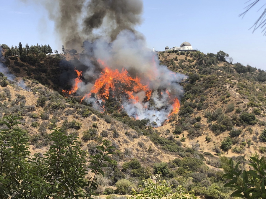 A wildfire burns on the hills surrounding the famous Griffith Observatory in Los Angeles Tuesday, July 10, 2018. Los Angeles Fire Department officials say the blaze has burned about two dozen acres of dry brush but its forward spread is stopped and crews have it nearly surrounded. Water-dropping helicopters are aiding firefighters on the ground.