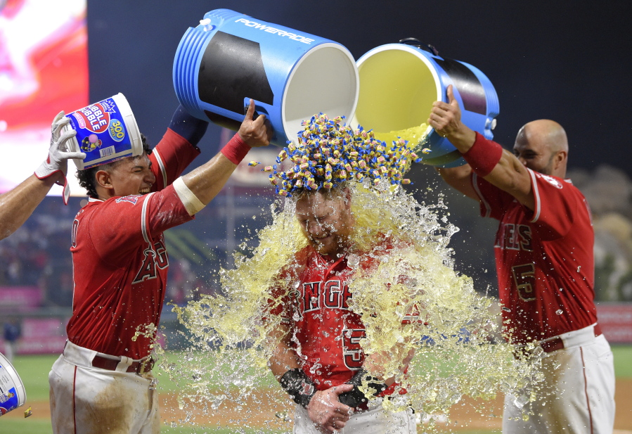 Los Angeles Angels’ Kole Calhoun, center, is doused by Jose Briceno, left, and Albert Pujols, and showered with bubble gum by another player, after hitting a walk-off home run during the 10th inning of a baseball game against the Seattle Mariners on Friday, July 27, 2018, in Anaheim, Calif. The Angels won 4-3. (AP Photo/Mark J.