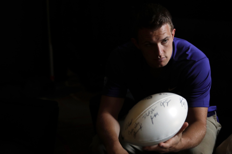 Washington quarterback Jake Browning hands the ball to head coach Chris Petersen, not pictured, in a holding room at the Pac-12 Conference NCAA college football media day in Los Angeles, Wednesday, July 25, 2018. (AP Photo/Jae C.
