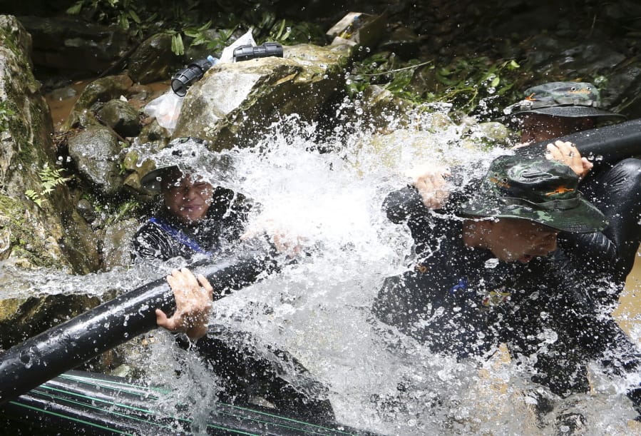 Thai soldiers try Saturday to connect water pipes that will divert water from the cave in Mae Sai, northern Thailand, where 12 boys and their soccer coach have been trapped since June 23.