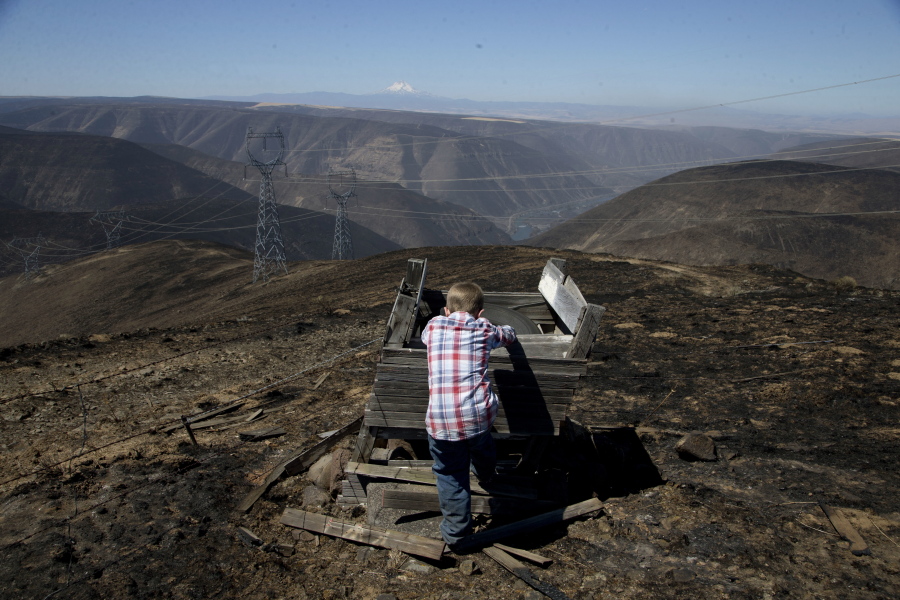 A boy stands in an area damaged by the Substation Fire on Friday near Moro, Ore. The blaze burning near The Dalles, Ore., has scorched more than 70,000 acres and is 15 percent contained, officials said Friday. One person, a farmer, has died in the fire.