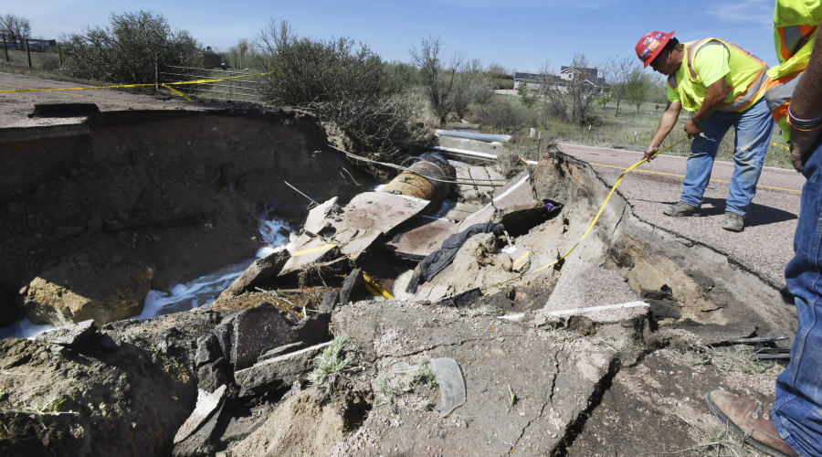 Utility worker Dino Rodriguez measures 16 feet to the bottom of a hole that was created in Old Pueblo Rd. south of Fountain, Colo., Tuesday, July 24, 2018. The massive hole happened after rain flooded the road during Monday's storm. A vehicle fell into the culvert and when the Hanover Fire Dept. responded to the cave-in, their fire truck fell into the hole on Tuesday. Both vehicles were removed early Tuesday morning. Two firefighters were injured and one person was airlifted from the scene.