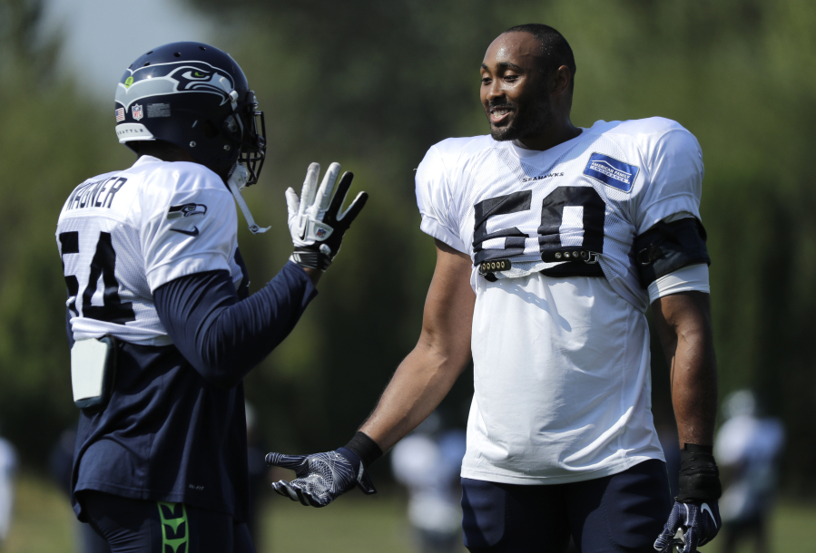 Seattle Seahawks linebackers Bobby Wagner, left, and K.J. Wright, right, talk during NFL football training camp, Sunday, July 29, 2018, in Renton, Wash. (AP Photo/Ted S.