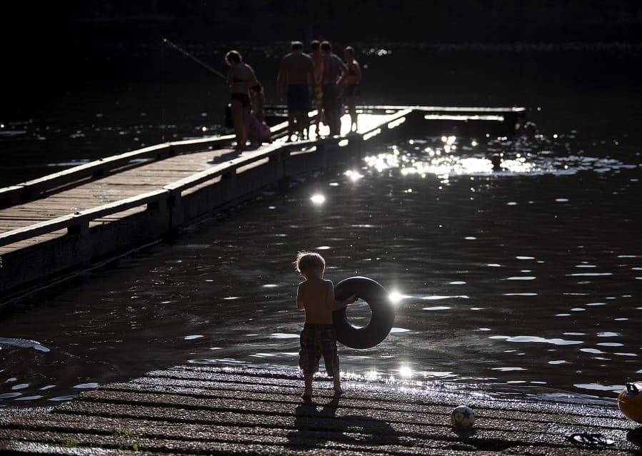 Samuel Slivkov, 3, of Vancouver makes his way into a shallow area of water while cooling off from hot summer temperatures with a crowd of swimmers on the evening of July 17 at Battle Ground Lake State Park.