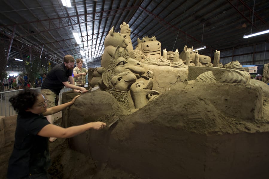 Sand sculptors Sue McGrew, from left, Brian Thomas and Brandi Glenn put details on a 75-ton sandcastle Saturday in the Grand Pavilion at the Clark County Fair. Brandi Glenn and her husband, Greg Glenn, own Sandscapes, a California-based sandcastle-building company.