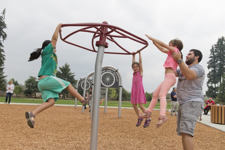 Children play at the grand opening of Otto Brown Neighborhood Park. Bryan Kast, right, whose family helped name the park, plays with his daughters — from left, Zeana, 8, Kiyla, 6, and Inga, 7. The park is 7.9 acres and named after Otto Alexander Brown, a Hockinson native who made a wooden bicycle.