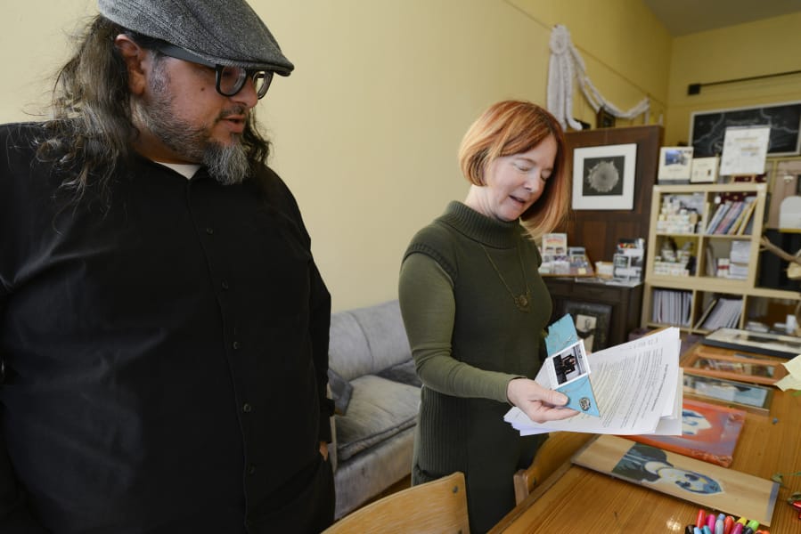 Leah Jackson, right, peruses contributions to a community art exhibit at Angst Gallery with Christopher Luna, a Vancouver poet and artist who works with her at the downtown Vancouver gallery.