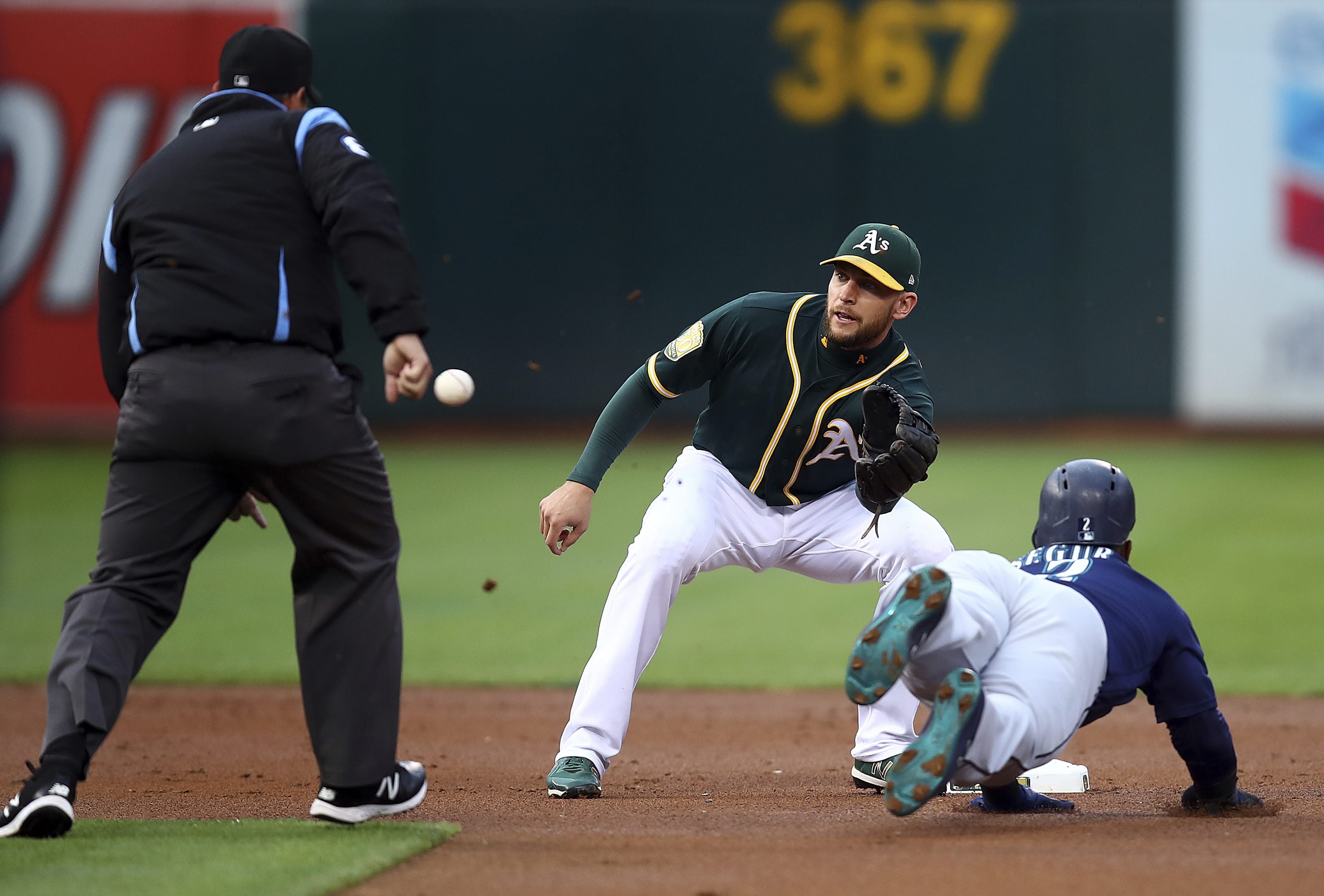 Oakland Athletics' Jed Lowrie waits for the ball to tag out Seattle Mariners' Jean Segura, right, in the first inning of a baseball game Monday, Aug. 13, 2018, in Oakland, Calif.