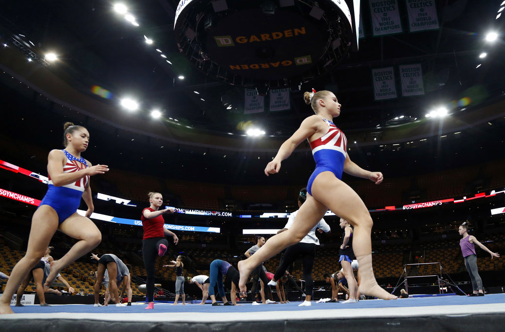 FILE - In this Aug. 15, 2018, file photo, Ragan Smith, right, warms up with other athletes during a training session at the U.S. Gymnastics Championships in Boston. The mandate to change the culture within USA Gymnastics will take years. Yet there are small signs at the U.S. Championships that the process has already begun under new high performance director Tom Forster, from quiet chats during the middle of meets to impromptu phone calls of encouragement.