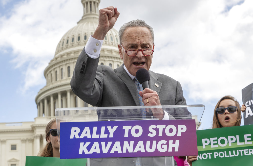 FILE - In this Aug. 1, 2018 file photo, Senate Minority Leader Chuck Schumer, D-N.Y., joins protesters objecting to President Donald Trump's Supreme Court nominee Brett Kavanaugh at a rally Capitol in Washington.  Schumer, who plans to meet Kavanaugh privately early this week, is methodically building arguments that would help vulnerable Democratic senators in Trump-loving states vote “no,” while avoiding explicitly pressuring them. But the party’s restive left-wing says he’s not aggressively rallying Democratic lawmakers to oppose the nomination, inhibiting the momentum needed to galvanize voters and maybe even win the uphill fight. (AP Photo/J.
