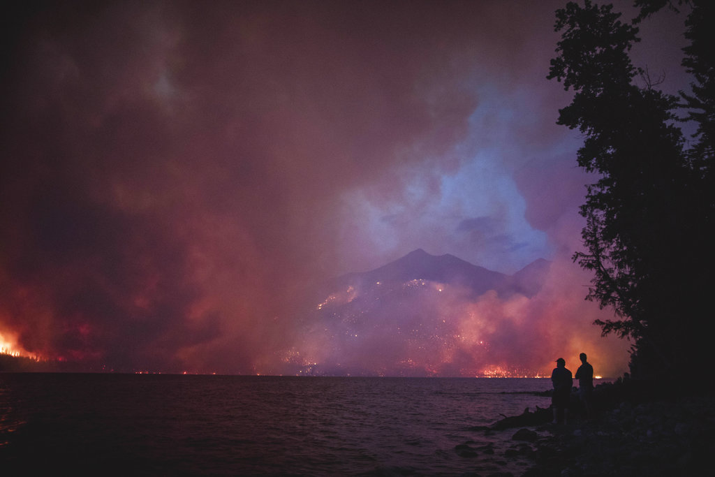 FILE--In this Aug. 12, 2018, file photo provided by the National Park Service, the Howe Ridge Fire is seen from across Lake McDonald in Glacier National Park, Mont. It's a good news, bad news situation for firefighters working in Glacier National Park. While the forecast calls for cooler weather and higher humidity, gusting winds and thunderstorms also are predicted.