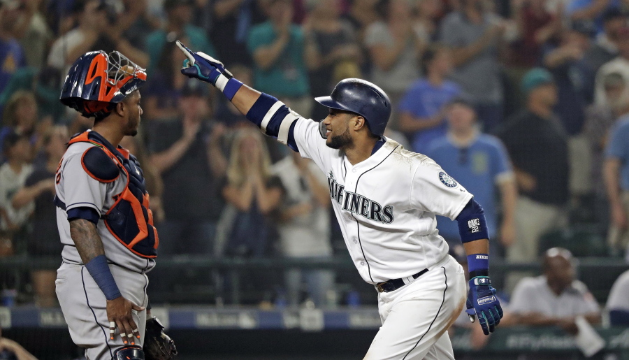 Seattle Mariners’ Robinson Cano, right, points toward the stands as he passes Houston Astros catcher Martin Maldonado at home on his three-run home run in the eighth inning of a baseball game, Monday, Aug. 20, 2018, in Seattle.
