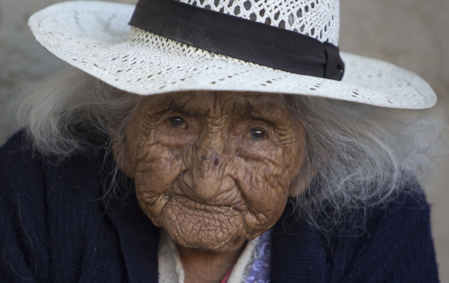 117-year-old Julia Flores Colque eyes the camera while sitting outside her home in Sacaba, Bolivia. Her national identity card says Flores Colque was born on Oct. 26, 1900 in a mining camp in the Bolivian mountains. At 117 and just over 10 months, she would be the oldest woman in the Andean nation and perhaps the oldest living person in the world.