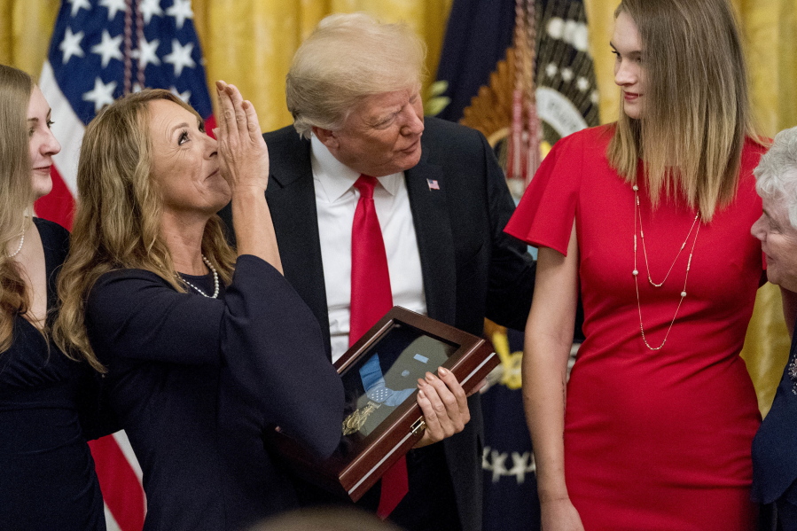 Valerie Nessel, second from left, accompanied by family members, blows a kiss to the sky as she accepts a Medal of Honor from President Donald Trump, center, for her husband, Air Force Tech. Sgt. John A. Chapman, on Wednesday at the White House.