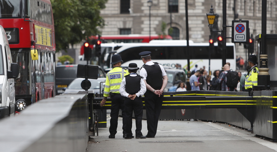 London Metropolitan Police Commander Adrian Usher, head of the Diplomatic and Royal Protection, right, talks to police officers on duty at the barrier outside the Palace of Westminster, in London, Wednesday, Aug. 15, 2018. Police on Tuesday flooded the streets around Palace of Westminster buildings and cordoned off the area that attracts tourists as well as lawmakers after a speeding car plowed into cyclists and crashed into a barrier outside the House of Lords.
