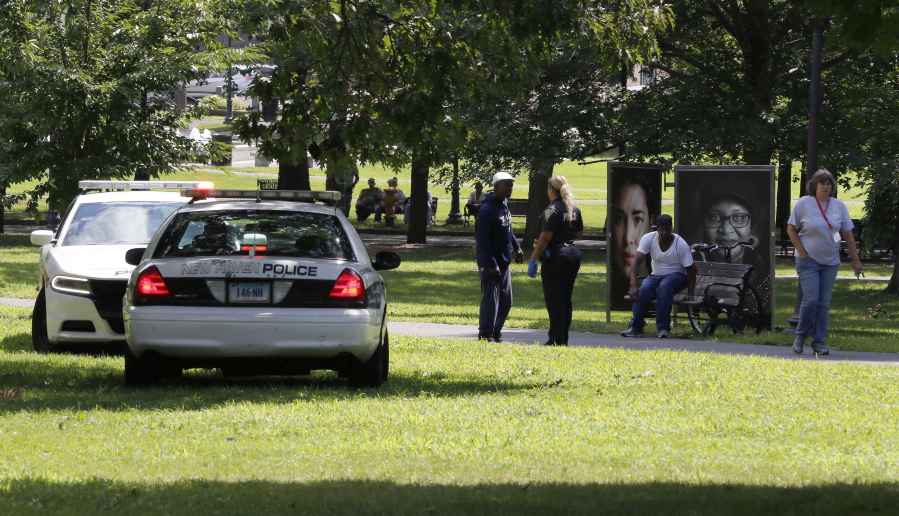 A police officer speaks to a man walking on New Haven Green on Wednesday in New Haven, Conn. A city official said more than a dozen people fell ill from suspected drug overdoses on the green and were taken to local hospitals.