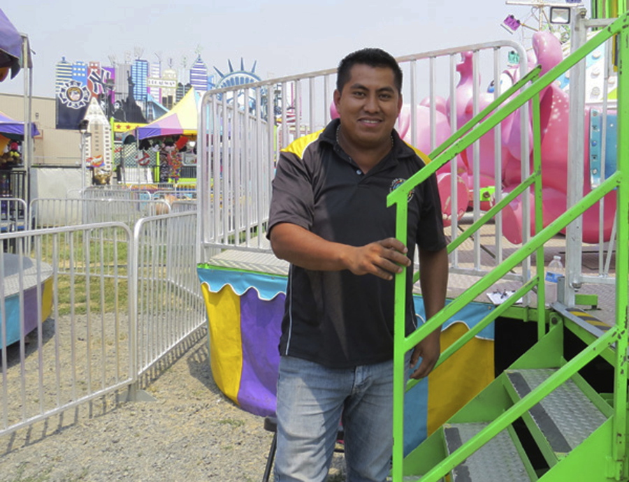 Jorge Luiz, 28, stands outside the flying elephants, vamos elephantes, a ride for kids at the Klamath County Fair on August 1. He is from Veracruz, Mexico. He travels with the crew weekly, and has been with the Wold carnival for 7 seasons.