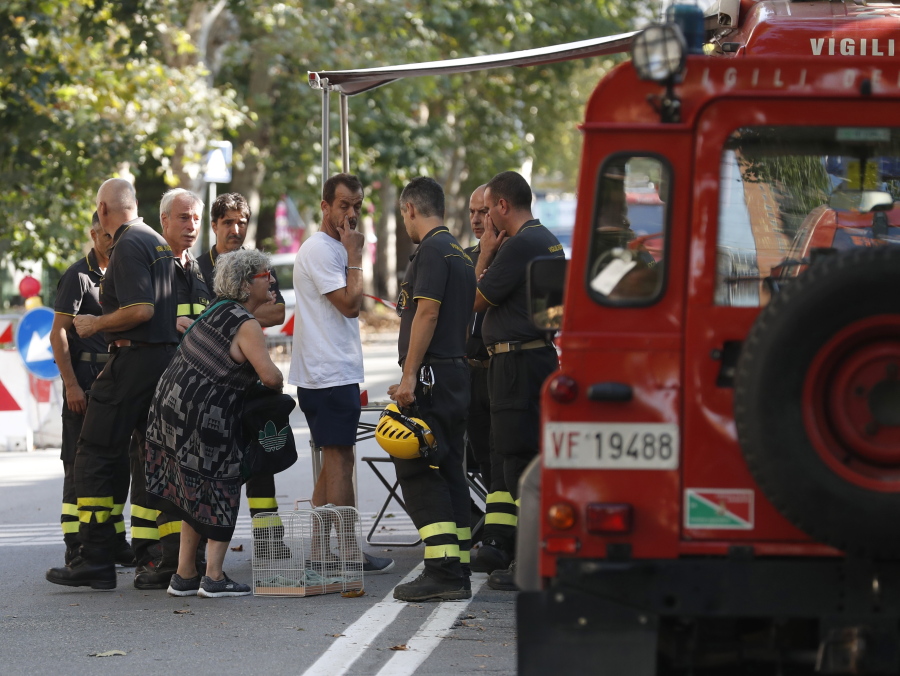 A woman talks to firefighters as they accompany residents to get their belongings from their homes, in Genoa, Italy, on Thursday. Authorities worried about the stability of remaining large sections of a partially collapsed bridge evacuated about 630 people from nearby apartments, some practically in the shadow of the elevated highway.