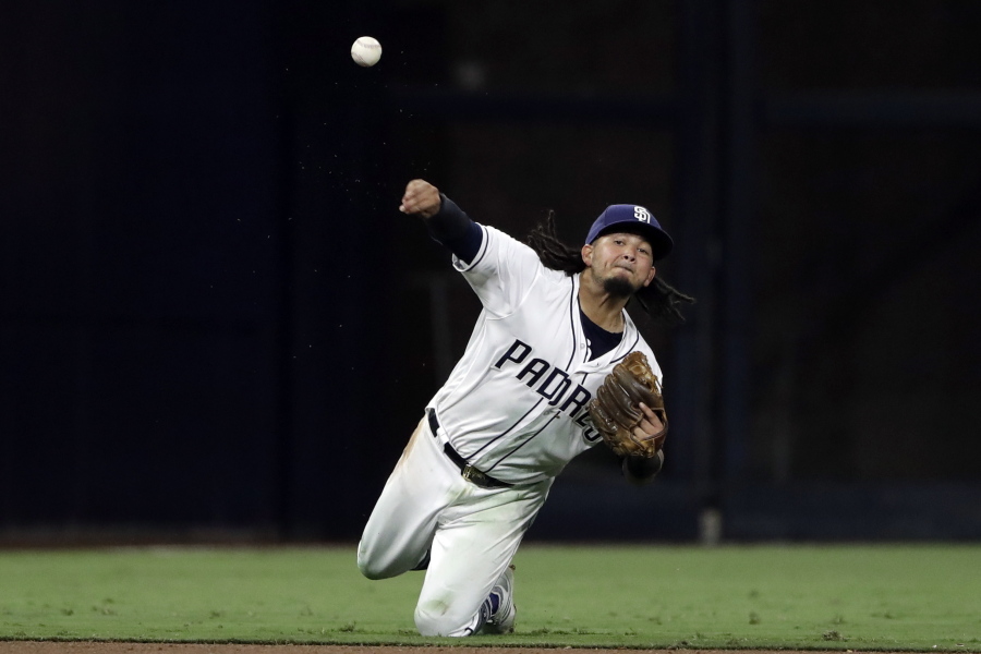 San Diego Padres shortstop Freddy Galvis throws on his knees for the out at first on Seattle Mariners’ Nelson Cruz during the sixth inning of a baseball game, Tuesday, Aug. 28, 2018, in San Diego.