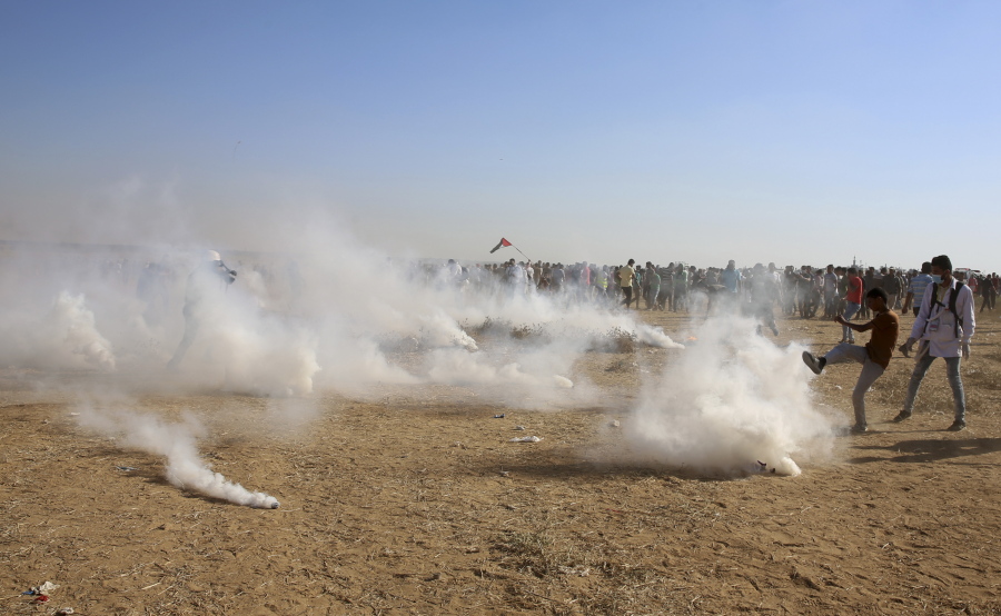 A protester tries to kick back a teargas canister fired by Israeli troops Friday near the southern Gaza Strip border with Israel.
