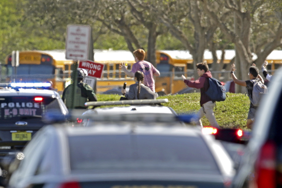 Students run with their hands in the air following a shooting Feb. 14 at Marjory Stoneman Douglas High School in Parkland, Fla. Authorities released video Wednesday showing blurred images of students running from the building.
