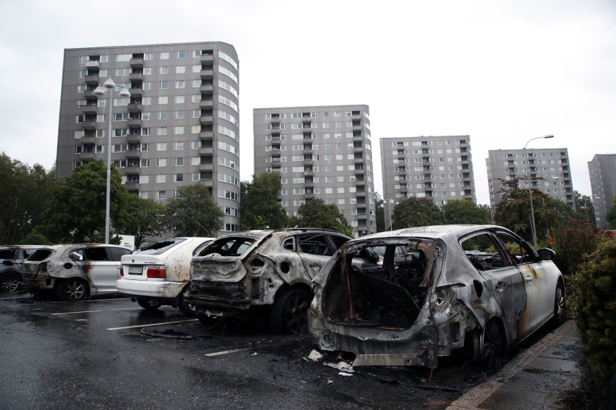 Burned cars are parked Tuesday at Frolunda Square in Gothenburg, Sweden. Masked youths torched dozens of vehicles overnight and threw rocks at police.