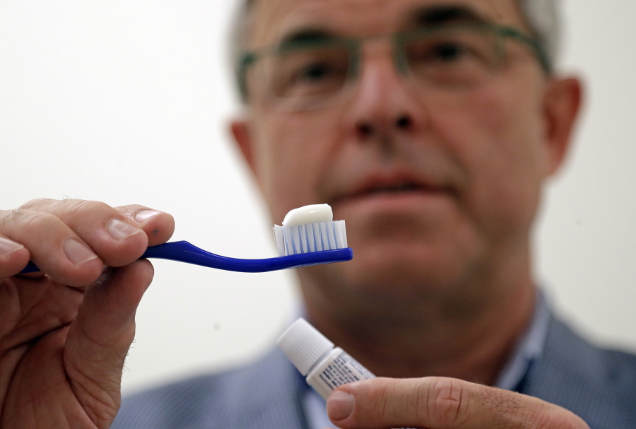 Philippe Hujoel, a dentist and University of Washington professor, holds a toothbrush and toothpaste as he poses for a photo in an office at the school in Seattle. Dental health experts worry that more people are using toothpaste that skips the most important ingredient - the fluoride - and leaves them at a greater risk of cavities.