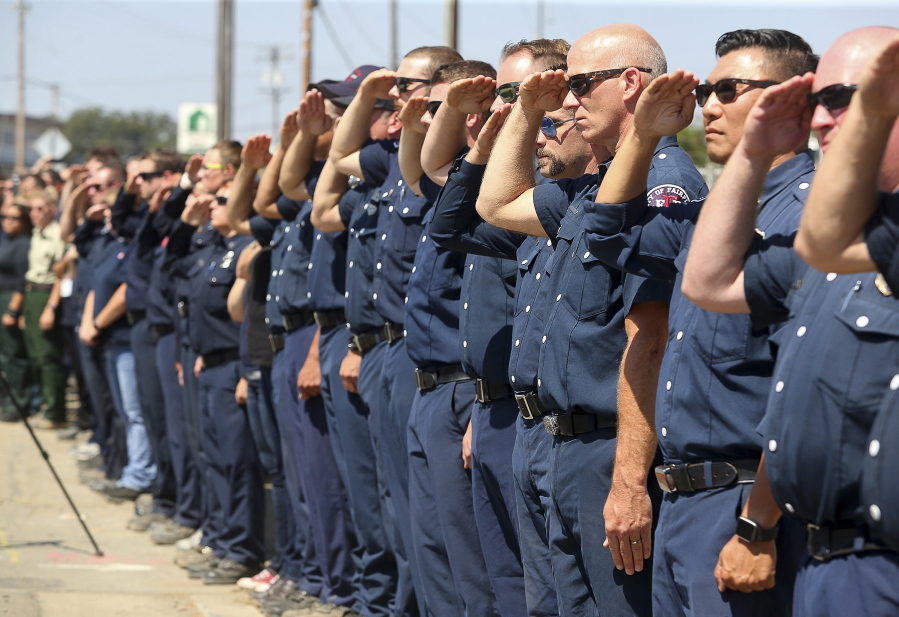 Firefighting personnel from various agencies salute as the procession for Battalion Chief Matthew Burchett travels along North State Street on Wednesday in Ukiah, Calif. Burchett was hit by a falling tree and died while fighting the largest blaze in California history, the Mendocino Complex Fire north of San Francisco.