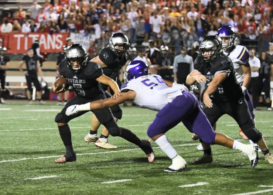 Union quarterback Lincoln Victor looks to elude a Puyallup tackler in the Titans’ 38-31 win over Puyallup.