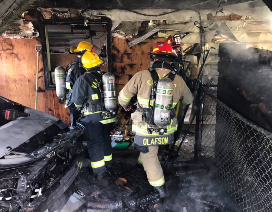 Vancouver Fire Department and Clark County Fire District 6 firefighters root through a garage Thursday afternoon in the Barberton area north of Vancouver.