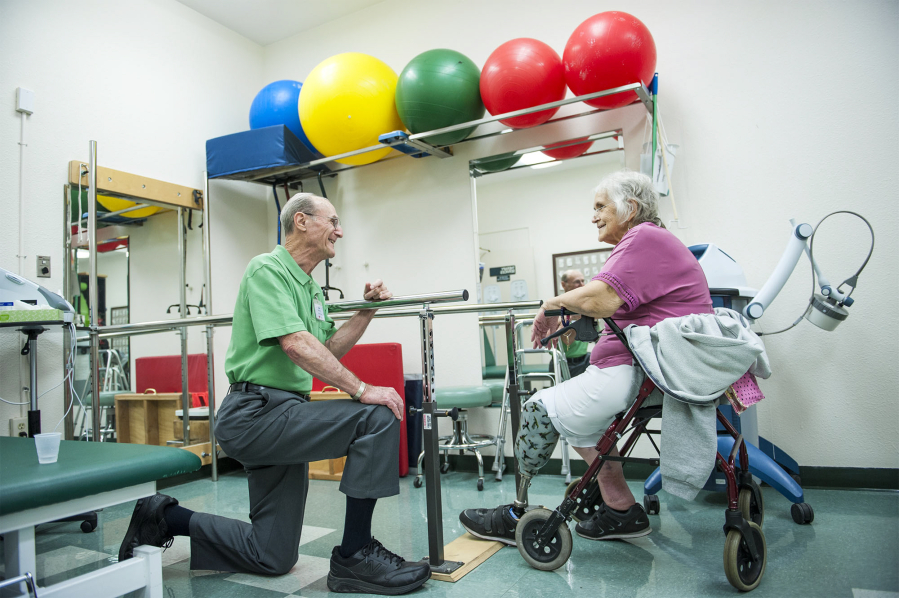 Woodland Care Center physical therapist Jim Ferris, 79, left, works with Barbara, who preferred to not give her last name, on her range of motion and strength while walking on her prosthetic leg. Ferris is part of a growing number among seniors to continue working later in life.