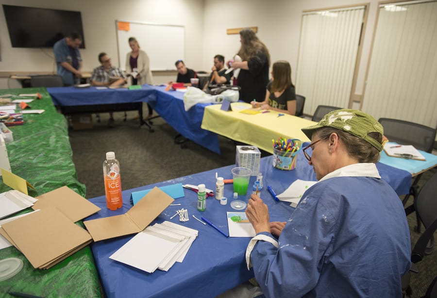 Vancouver artist Linda Harbaugh, right, leads an art therapy class at the National Alliance on Mental Illness Southwest Washington as participants create a pocketbook journal.